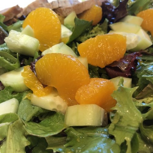 mandarin oranges on top of tossed salad with avocado and cucumber
