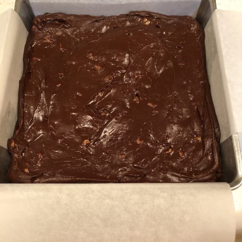 chocolate fudge with pecans in pan with parchment