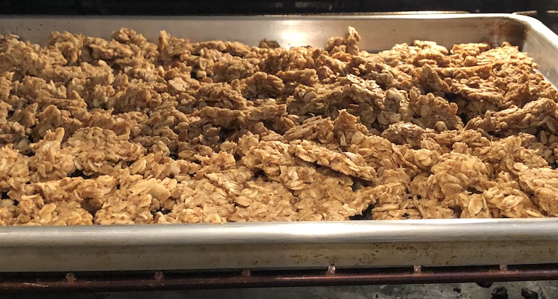 Big chunks of nut free, gluten free granola on a rimmed baking sheet in the oven