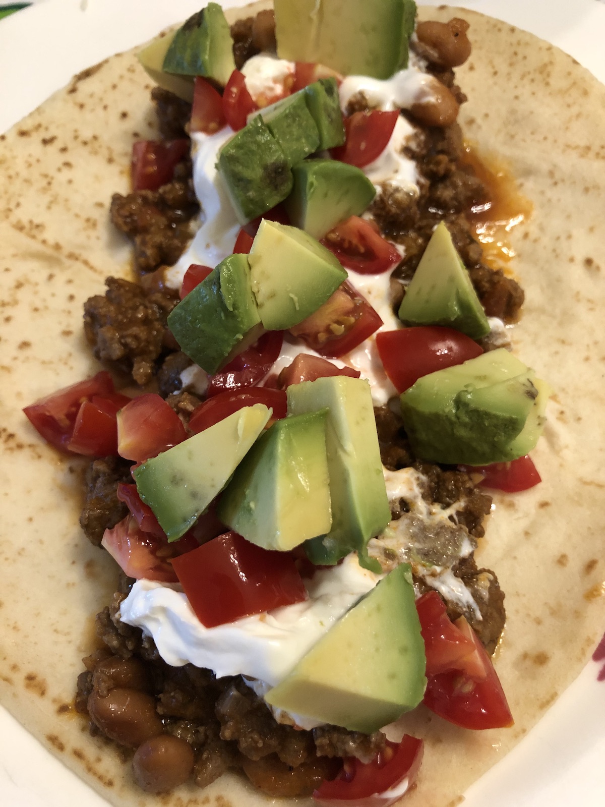 Taco Meat and Beans with avocado, tomato & sour cream on a flour tortilla