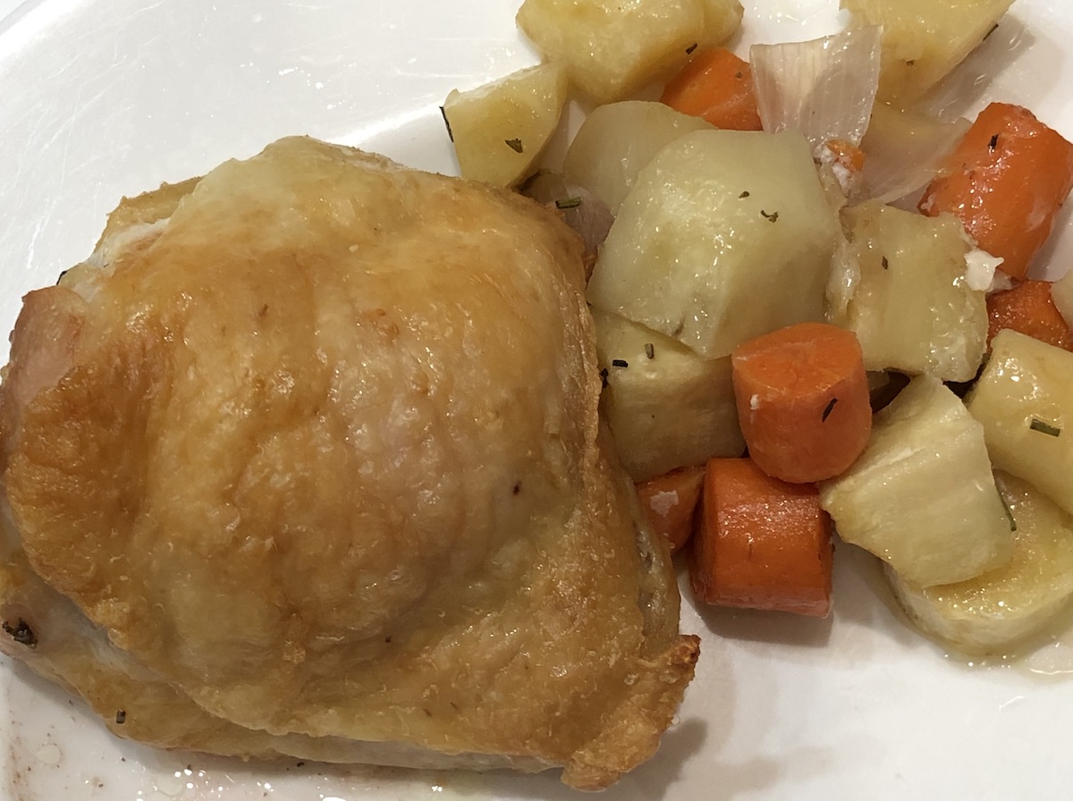 roasted chicken thigh with pieces of roasted root vegetables: carrots, potatoes and parsnips
