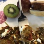 eggplant_tomato_gratin on fork and on plate with kiwi half, plum, sausage in bun