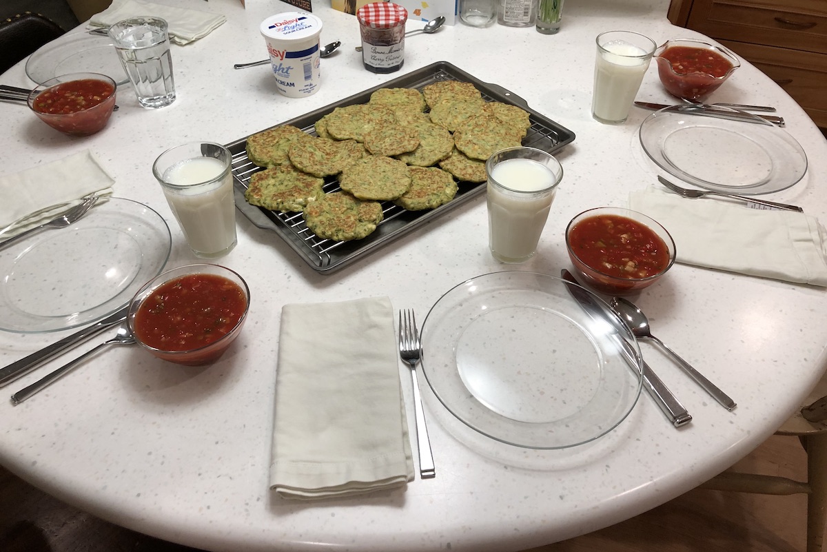 Table set with 4 place settings. Gluten free zucchini pancakes in the center with gazpacho at each place.