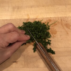chopping parsley on a wooden cutting board