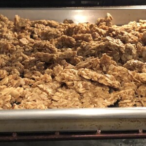 Big chunks of nut free, gluten free granola on a rimmed baking sheet in the oven